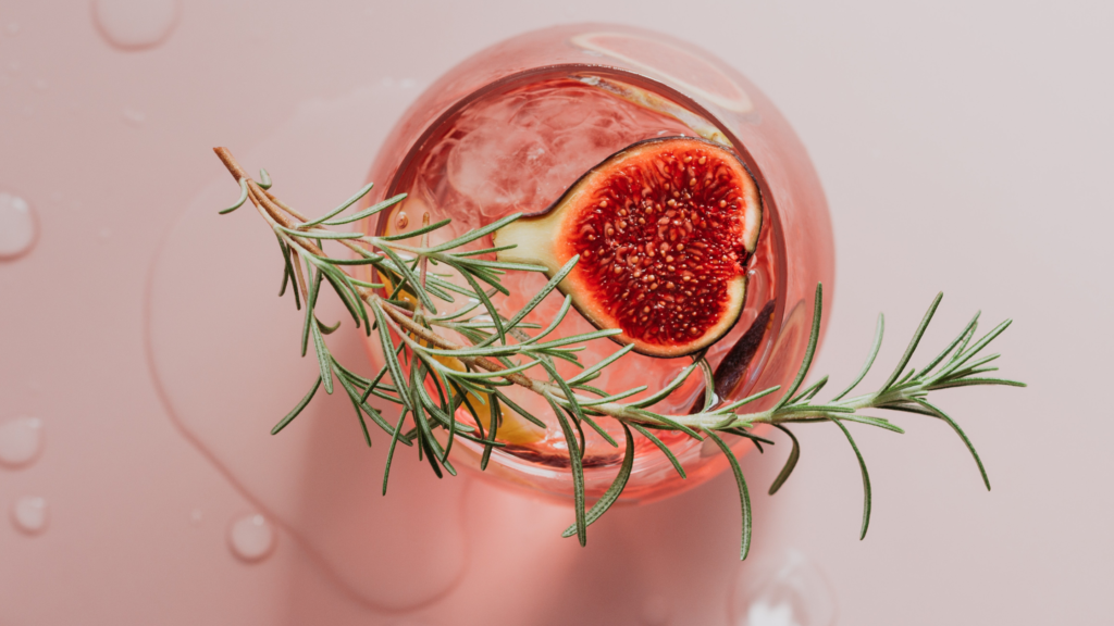 Valentine's Day pink cocktail with a fig and rosemary sprig.