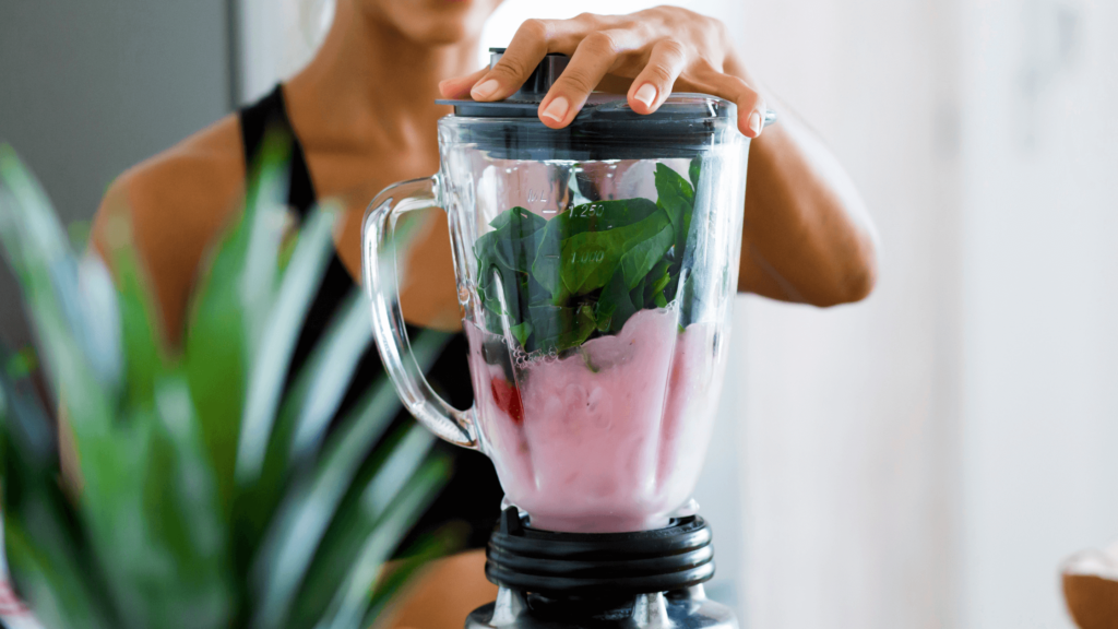 Woman blending berry matcha smoothie with spinach.