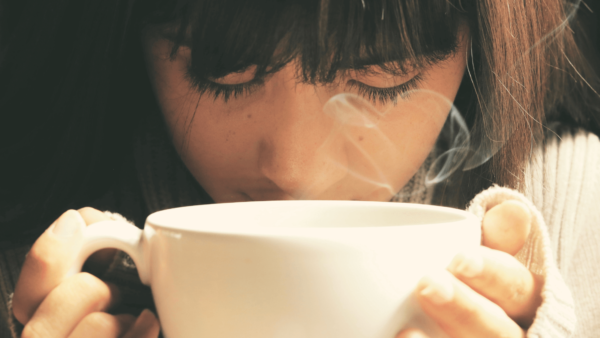 tea mindfulness - a woman sipping from a cup of tea with closed eyes.